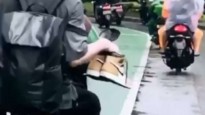 Penumpang Ojek Online rela nyeker dan menjinjing sepatunya