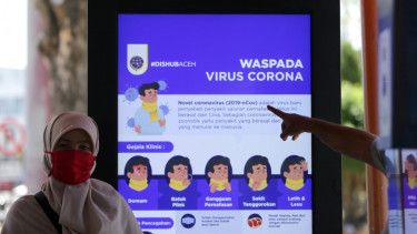 Warga melintas di samping papan informasi tentang virus Corona di halte