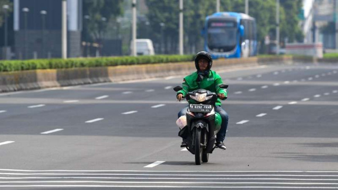 Driver ojek online (Ojol) melintasi Jalan MH Thamrin, Jakarta Pusat.