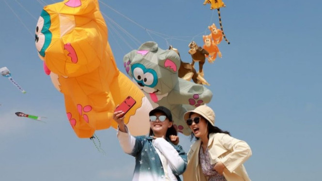 Warga berfoto dengan layang-layang di Weifang, Shandong (02/05).-Getty Images

