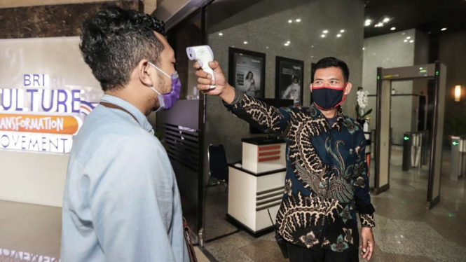 Pengecekan suhu tubuh dan kewajiban menggunakan masker saat penerapan new normal di BRI.