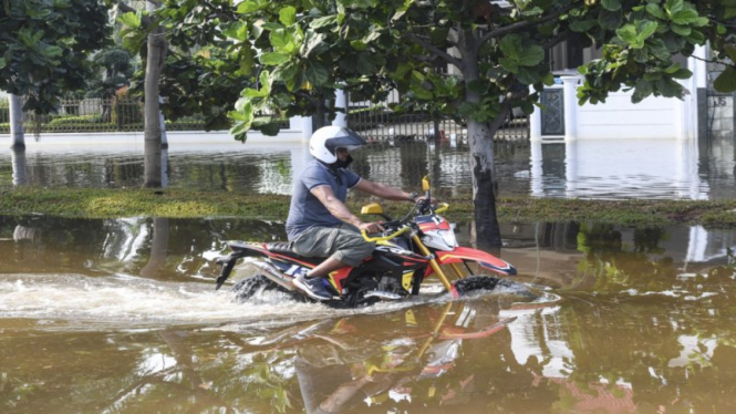 Pengendara motor melintas saat banjir rob menggenangi Kompleks Pantai Mutiara 