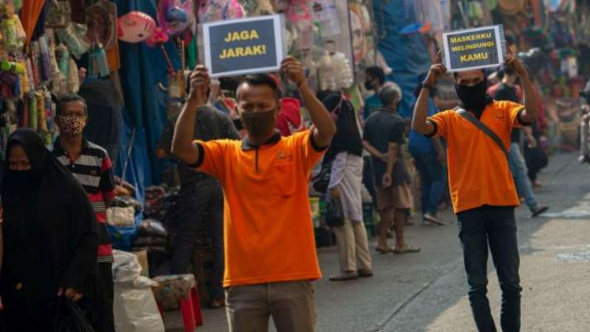Petugas pengelola pasar berkampanye pencegahan COVID-19 dengan membawa poster berisi pesan di Pasar Jatinegara, Jakarta, Kamis (11/6/2020). 