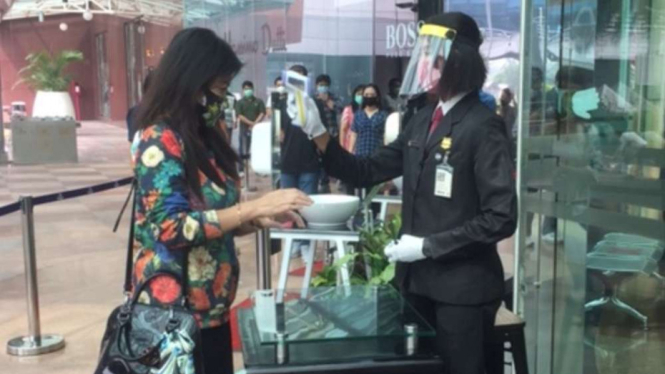 Pengecekan suhu tubuh oleh petugas kepada pengunjung Pondok Indah Mal.