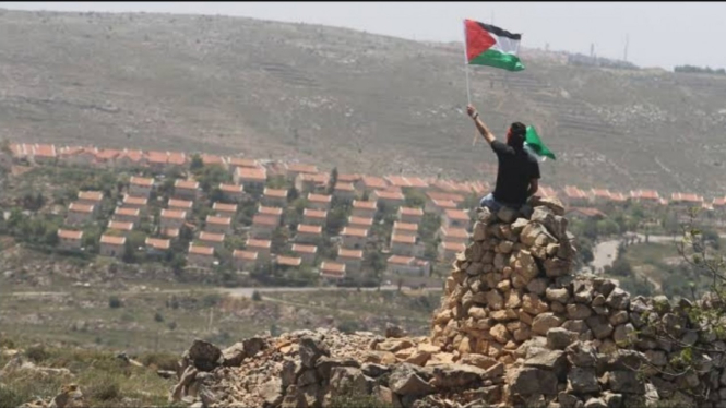 Seorang pria mengibarkan bendera Palestina di Tepi Barat. 