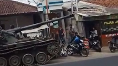 Pria memindahkan motor usai kecelakaan tank