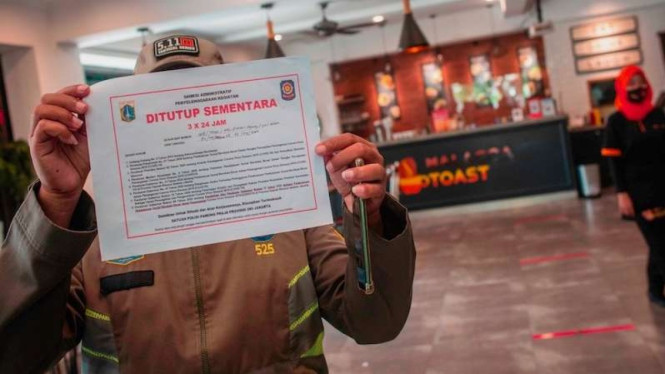 Petugas Satpol PP menutup suatu restoran yang menyediakan layanan makan di tempat saat razia PSBB Jakarta ( foto ilustrasi)