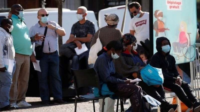 Warga Prancis di Paris saat menunggu bus di tengah pandemi COVID-19.