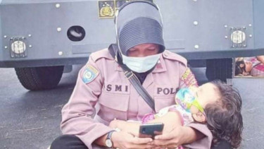 Aipda Ismi Andri Nurwati menggendong anaknya saat bertugas.