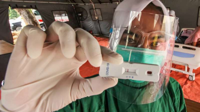 Ilustrasi petugas medis menunjukkan hasil screening rapid test COVID-19