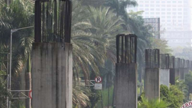 Sejumlah kendaraan melintas di samping tiang pancang proyek monorel.
