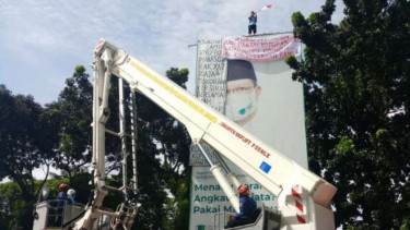 Petugas Pemadam Kebakaran mengevakuasi Agustinus yang memanjat papan reklame.