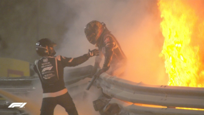 Pembalap tim Haas, Romain Grosjean, sedang diselamatkan usai mobilnya terbakar. 