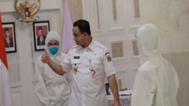 Gubernur DKI Jakarta Anies Baswedan mengikuti rapat virtual didamping petugas lengkap dengan APD
