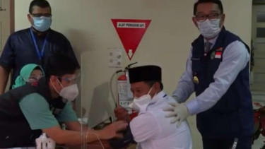 Wakil Gubernur Jawa Barat Uu Ruzhanul Ulum (duduk, kanan) didampingi sang gubernur Ridwan Kamil saat disuntik vaksin COVID-19 di Bandung pada Kamis, 14 Januari 2021.