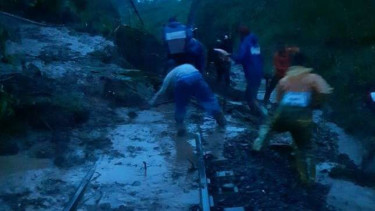 Petugas memperbaiki rel kereta api yang terimbun tanah longsor di Blitar. 