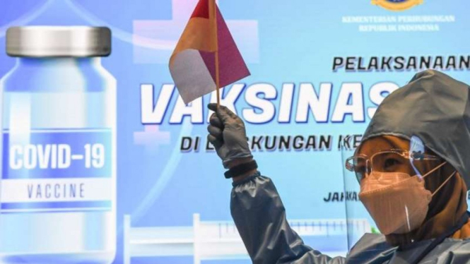 Tenaga kesehatan mengangkat bendera Merah Putih dalam pelaksanaan vaksinasi COVID-19 pada pegawai pemerintah di Jakarta tahun lalu.