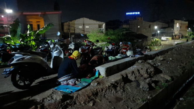 Korban Banjir di Cipinang Melayu, Siti Jubaedah tidur sambil sesekali menatap rumahnya yang terendam banjir.