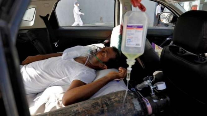 Seorang pasien dengan gangguan pernapasan berbaring di dalam mobil sambil menunggu untuk masuk rumah sakit COVID-19 untuk perawatan, di tengah penyebaran COVID-19 di Ahmedabad, India, Kamis 22 April 2021.