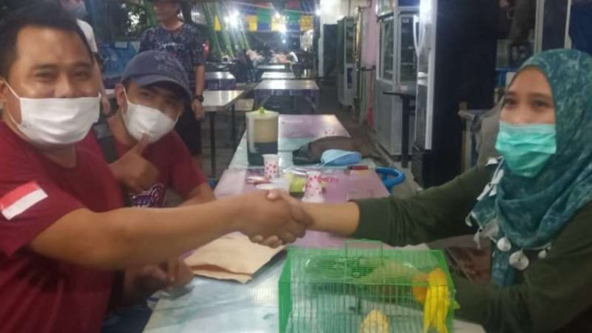 Didik Saputra (kiri), pria asal Kabupaten Lamongan, Jawa Timur, bertransaksi barter menukar satu mobil Honda CR-V tahun 2009 dengan sepasang burung love bird YF milik seorang wanita di Surabaya, Jumat malam, 28 Mei 2021.