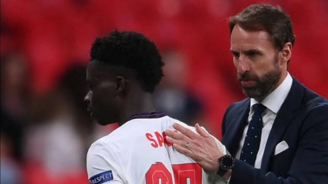 Manajer Timnas Inggris, Gareth Southgate, sedang menenangkan Bukayo Saka. 