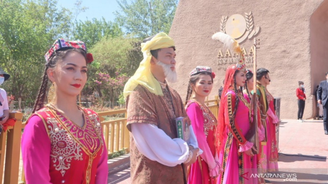 Perempuan etnis minoritas Muslim Uighur menyambut para wsiatawan di gerbang Kota Tua Kashgar, wilayah selatan Daerah Otonomi Xinjiang, China.