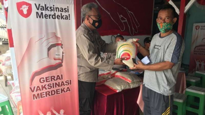 Polisi membagikan bantuan beras kepada warga yang melakukan vaksinasi
