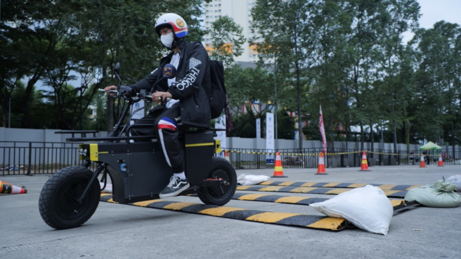 Pengunjung GIIAS 2021 mencoba mengendarai motor listrik