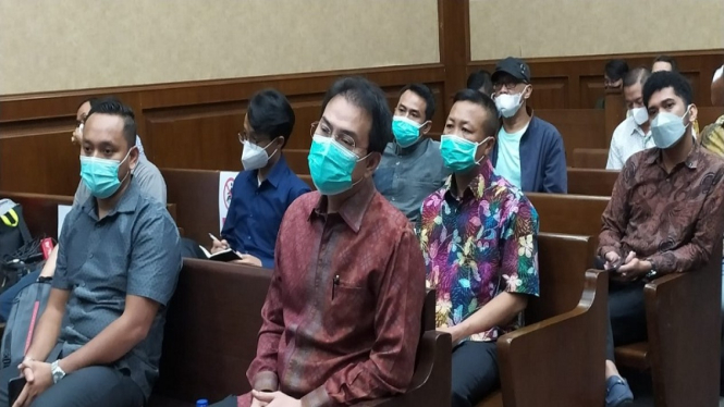 Mantan Wakil Ketua DPR Azis Syamsuddin (batik merah) menjalani sidang perdana
