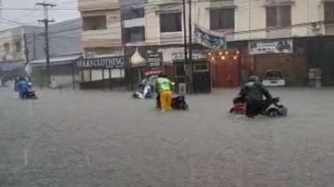Pengendara mendorong motor mereka yang mogok gegara banjir di Kota Makassar.