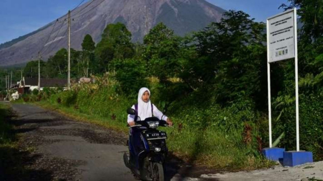 Seorang anak berangkat sekolah dengan latar belakang Gunung Semeru di Sumbermujur, Candipuro, Lumajang, Jawa Timur, Selasa, 14 Desember 2021.
