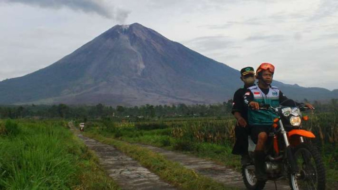 Relawan melintas saat Gunung Semeru mengeluarkan awan panas guguran melalui bukaan aliran lava baru di Desa Supiturang, Pronojiwo, Lumajang, Jawa Timur, Selasa, 21 Desember 2021.