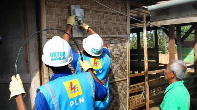 Petugas PLN saat memasang sambungan listrik untuk warga.