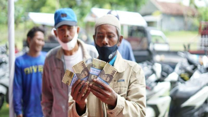 Warga menunjukan uang rupiah