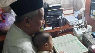 Ketua Dewan Pers M Nuh mengaji Alquran bersama cucunya. 