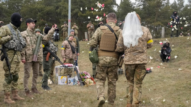 Tentara cadangan Ukraina melemparkan bunga ke pasangan yang menikah di garis depan. (AP: Efrem Lukatsky)