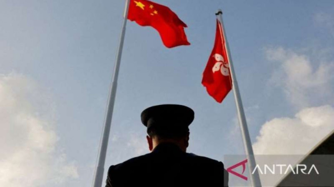 A policeman stands guard under Chinese (left) and Hong Kong flags (right).