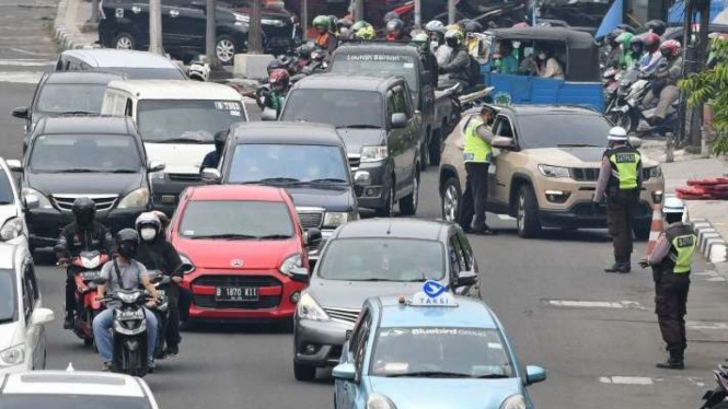 Polisi memberhentikan pengendara mobil yang melanggar ganjil genap.