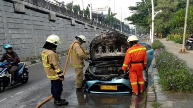Pemadam kebakaran memadamkan api yang menghanguskan mobil taksi di Sunter