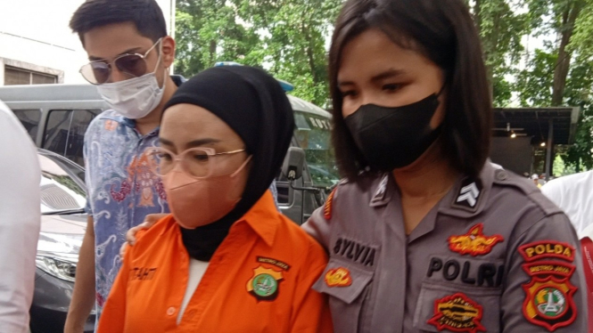 Medina Zein (kiri) menggenakan baju tahanan polisi.