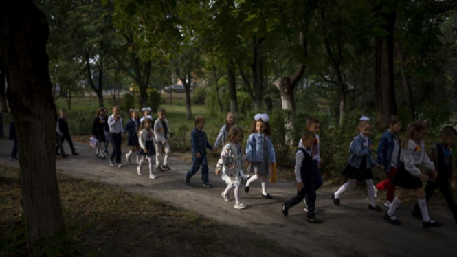 Siswa berjalan bersama memasuki kelas mereka pada hari pertama sekolah di sekolah umum di Irpin, Ukraina, Kamis, 1 September 2022.