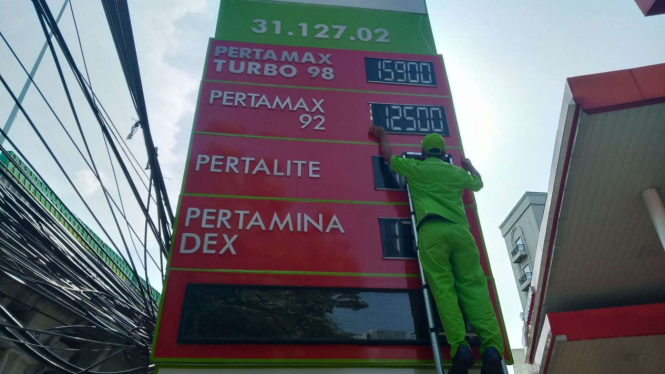 Petugas SPBU mengganti papan Harga BBM.