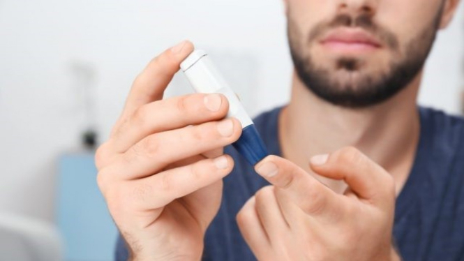 Seorang pria mengecek gula darah diabetes 