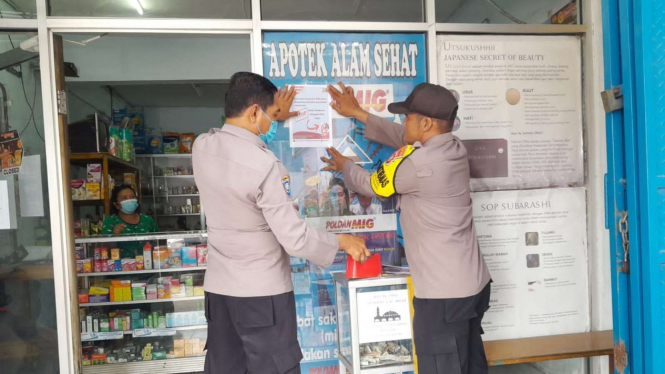 Ilustrasi Polisi memasang pamflet dan stiker di apotek terkait peringatan obat sirup 