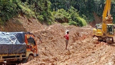 Sebanyak 150 truk dan kendaraan double cabin terjebak di jalan trans-Papua ruas Jayapura-Wamena. Tampak alat berat sedang berupaya membantu mengeluarkan truk.