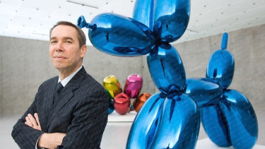 Jeff Koons berdiri di depan karya seninya, patung balon anjing.