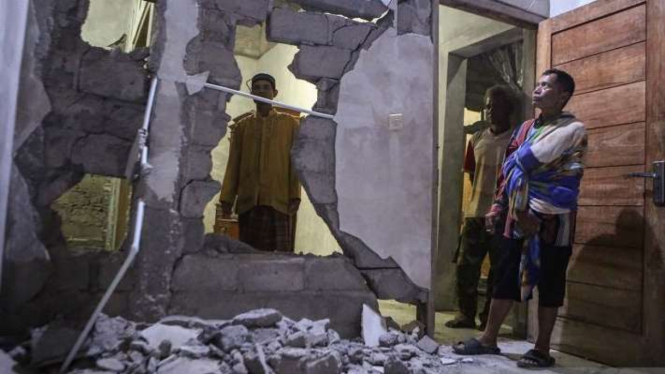 Warga menunjukkan rumah yang rusak akibat gempa.