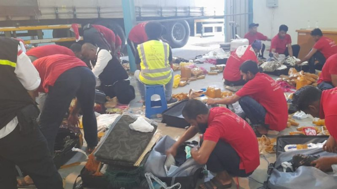 Petugas membongkar koper jemaah haji Indonesia yang membawa air zamzam.