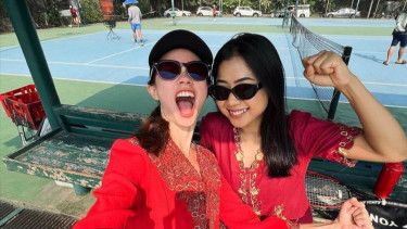 Yuki Kato mengenakan kebaya berwarna merah sambil bermain tenis.