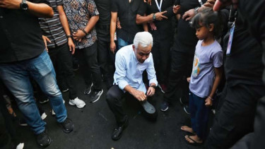 Ganjar Pranowo memperbaiki sandal jepit seorang anak kecil